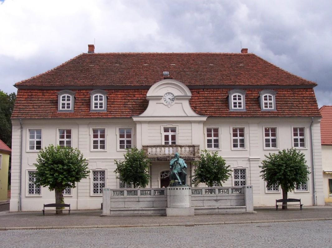 Abbildung 3: Ehemaliges Rathaus in Stavenhagen (heute Fritz-Reuter-Literaturmuseum) mit Statue Reuters; Quelle: Wikipedia